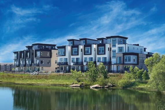 Modern buildings on the northwest side near a pond under a blue, partly cloudy sky